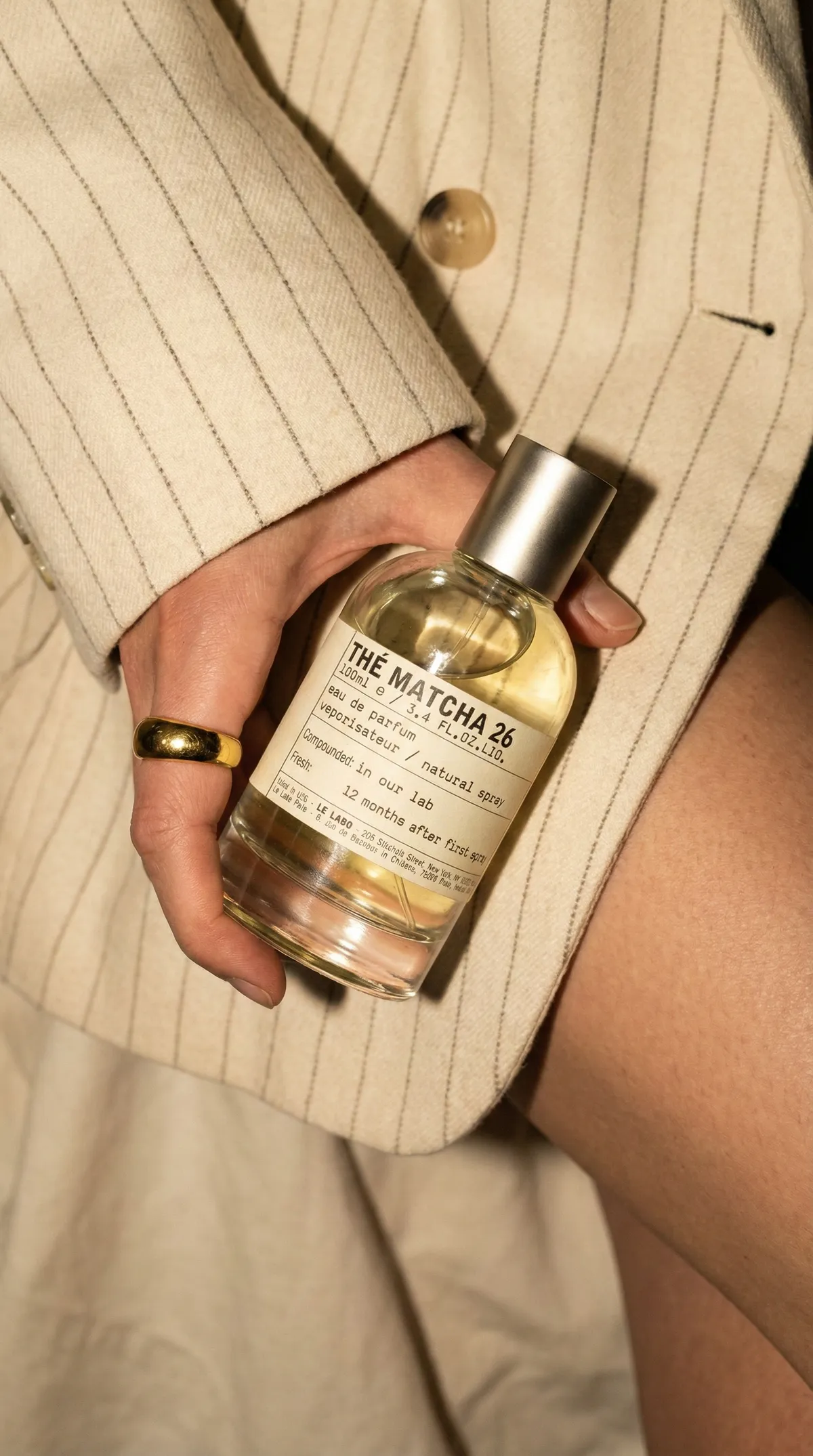 AI lifestyle photo of a hand holding a glass perfume bottle, styled with a gold ring