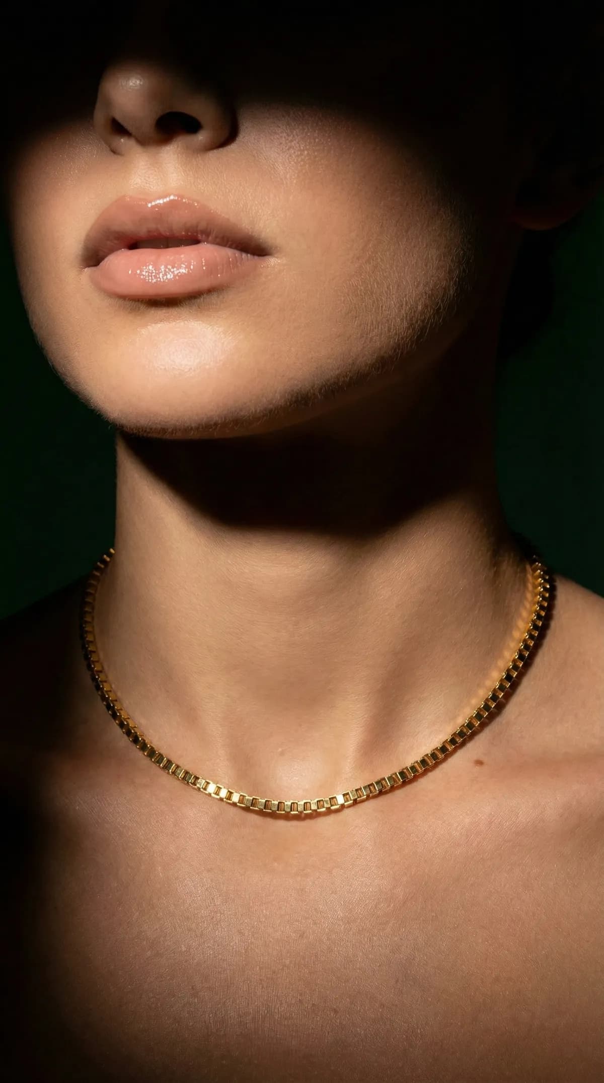 AI product photo of a gold chain necklace worn by a model against a dark green backdrop