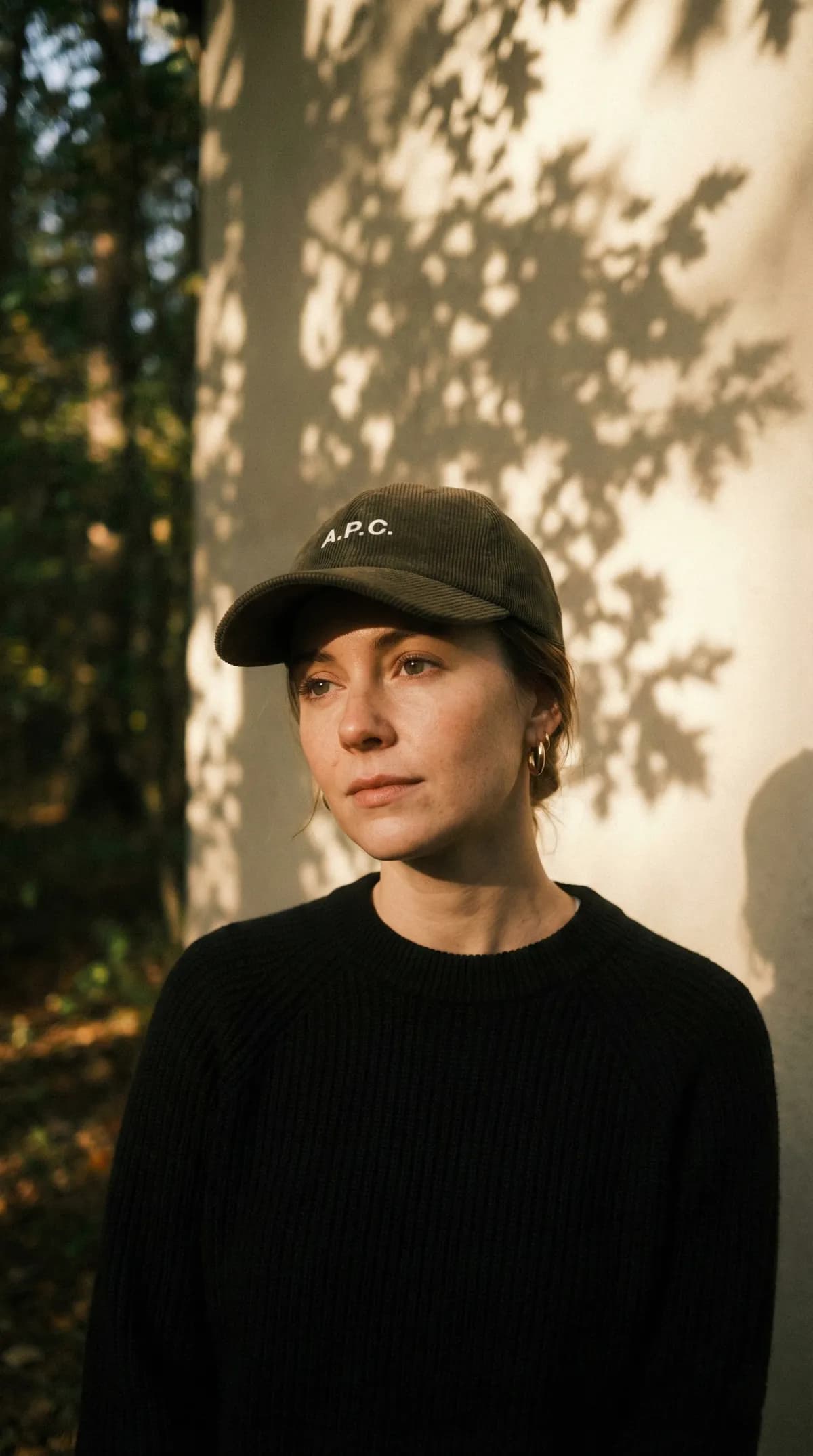 AI lifestyle photo of a model in a corduroy cap and gold hoop earrings at golden hour